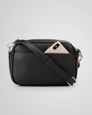 Black leather crossbody bag with a phone inside on a light gray background