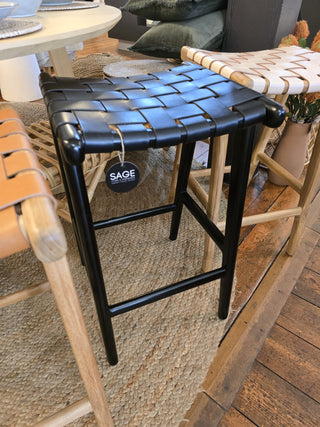 Black woven stool with a visible 'SAGE' tag in an indoor setting.
