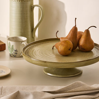 Ceramic platter with pears on a table with ceramic items in the background
