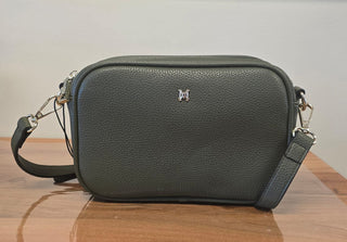 Green leather handbag with a visible brand logo on a wooden surface.