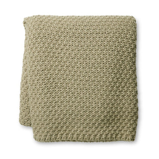 Folded beige knitted blanket on a white background