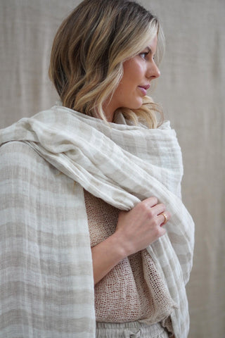 Woman wearing a beige shawl over her shoulders against a neutral background