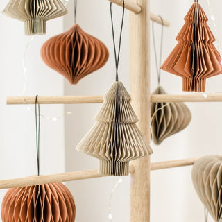 Decorative paper trees hanging on a wooden rack against a white background