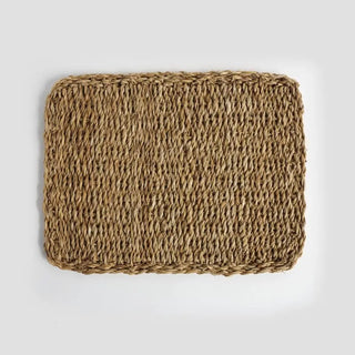 Rectangular woven mat made of natural fibers on a light gray background