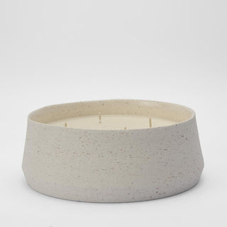 Ceramic candle holder with a white candle inside on a light gray background