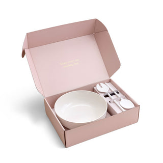 Pink gift box with a white bowl and cutlery set on a white background