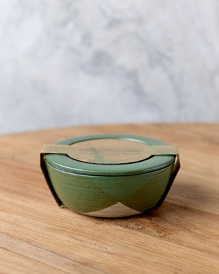 Green ceramic container with lid on a wooden surface