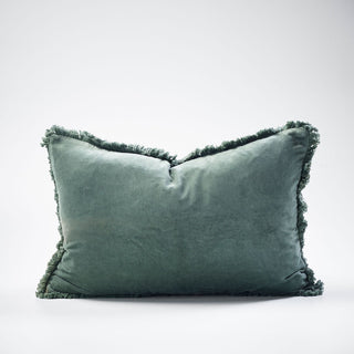 Green velvet pillow with frayed edges on a white background