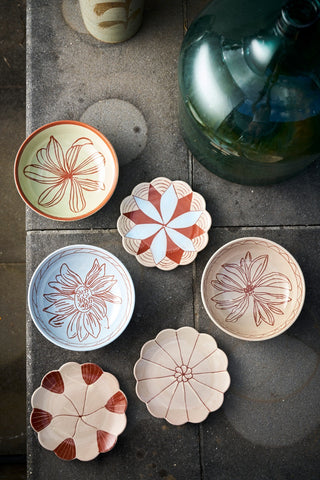 Set of ceramic dishes with floral patterns on a stone surface