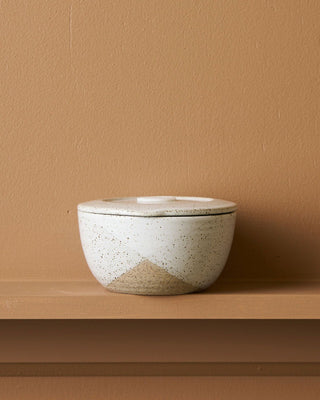 Ceramic bowl with a textured surface on a brown shelf against a matching brown wall