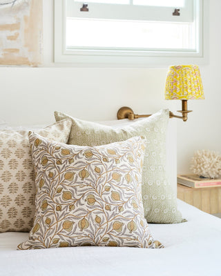 Decorative pillows on a bed with a lamp and window in the background