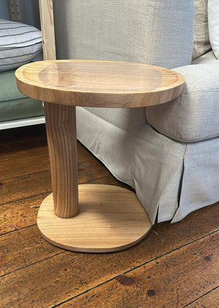 Wooden side table on a wooden floor with a sofa in the background