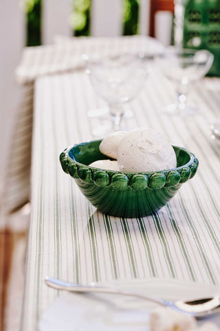 Green ceramic bowl with a white object on a textured surface