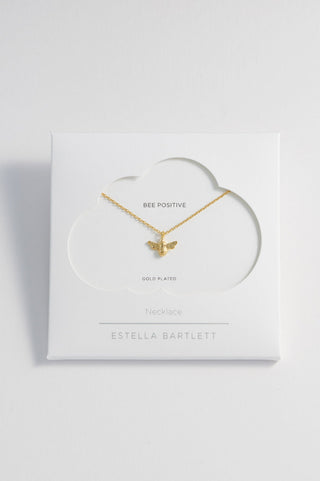 Gold butterfly necklace on a white heart-shaped card with 'Estella Bartlett' branding.