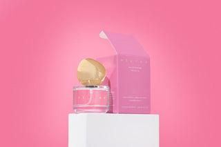 Perfume bottle with gold cap and pink packaging on a pink background