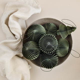 Decorative green fans in a brown bowl with a white cloth on a beige background