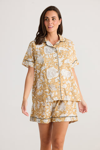 Woman wearing a yellow floral pajama set on a white background