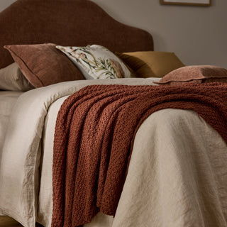 Neatly made bed with brown blanket and pillows in a bedroom setting