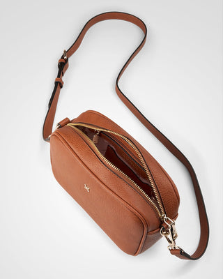 Brown leather crossbody bag with a visible brand logo on a light gray background