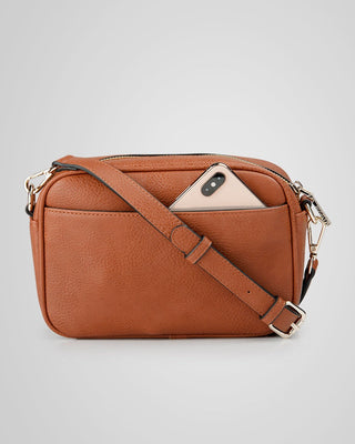 Brown leather crossbody bag with a phone inside on a light gray background