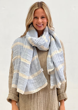 Woman wearing a light blue and beige striped scarf on a white background
