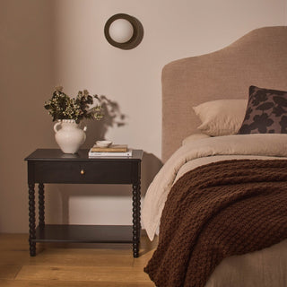 Bedroom with a nightstand and bed featuring decorative items.