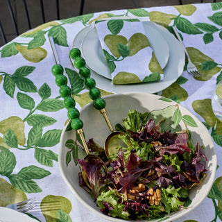 Bowl of salad with green beaded handles on a tablecloth with leaf pattern