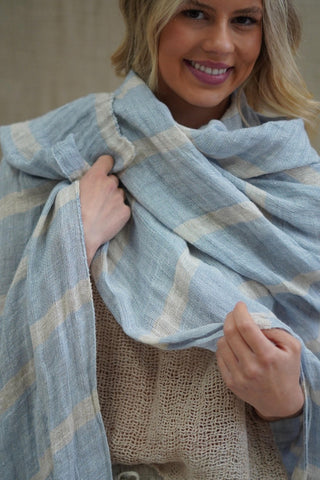 Woman holding a blue and beige plaid scarf