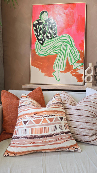 Decorative pillows on a sofa with a colorful painting in the background