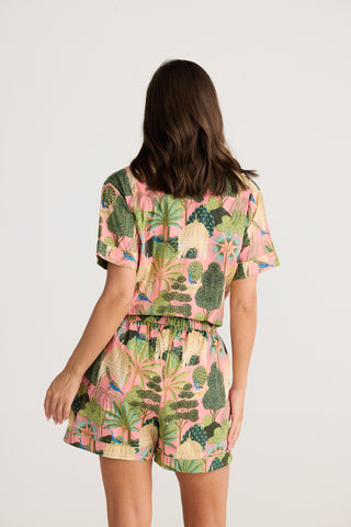 Person wearing a tropical patterned outfit on a plain background