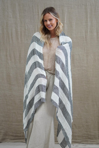 Woman wearing a gray and white striped poncho against a beige background