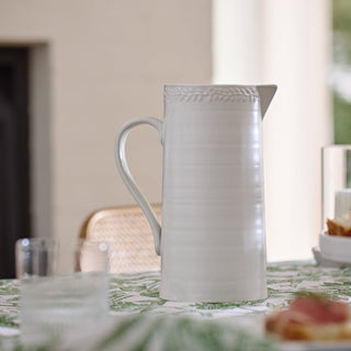 White ceramic pitcher on a table with a blurred background
