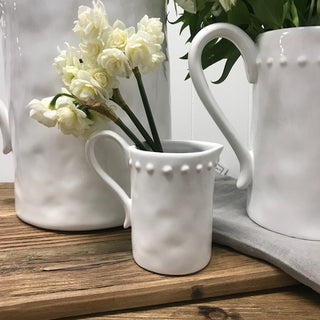 White ceramic mugs with decorative handles on a wooden surface