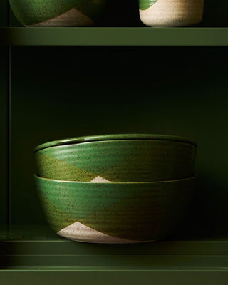 Green ceramic bowl on a dark green shelf