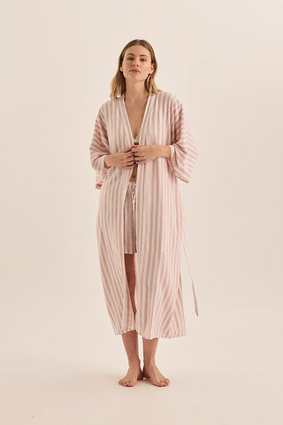 Woman wearing a pink striped robe on a beige background