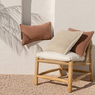 Wooden chair with cushions against a neutral wall
